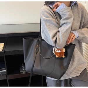 Détail d'un grand sac cabas en nylon noir avec bandoulière et pendentif en peluche