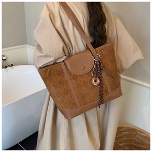 Detail of vintage brown quilted tote bag with suede texture and decorative charm pendant