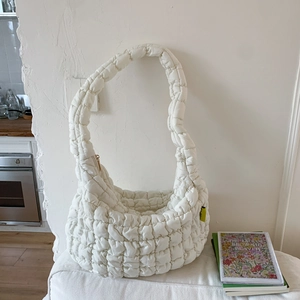 Close-up of white quilted cloud bag with puffer texture and premium gold zipper detail