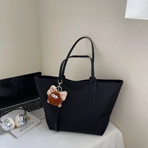 Détail du sac cabas noir avec pendentif monstre en peluche mignon et texture lisse