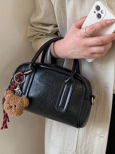 Schicke schwarze Handtasche aus Lederimitat mit Faltenoptik und Bärenanhänger