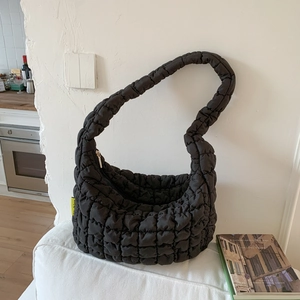 Detail of black quilted cloud bag texture and neon fashion tag on white sofa