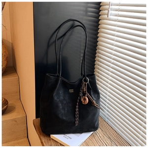 Detail of black suede tote bag with gold lettering and wooden ring tassel charm