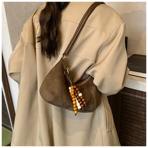 Dettaglio della borsa hobo in pelle scamosciata marrone con perline in legno su modella