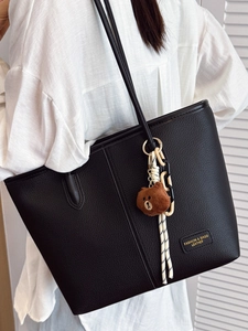 Retro black litchi pattern leather tote bag with cute brown bear charm on model's shoulder