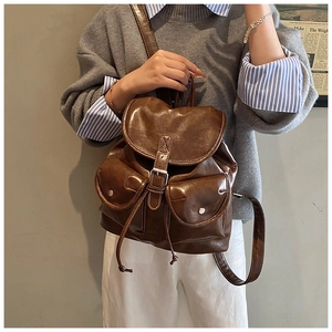 Détail d'un sac à dos vintage en cuir marron avec boucles métalliques sur modèle