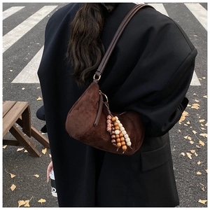 Dettaglio borsa a mezzaluna in camoscio marrone con decorazione in perline di legno