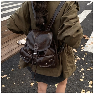 Détail du sac à dos vintage en cuir marron foncé avec coutures et fermoirs à boucle