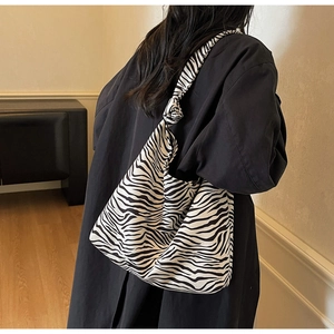 Knotted strap zebra pattern canvas shoulder bag shown worn by model in side-view