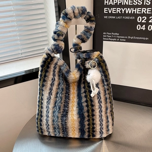 Detail of colorful striped faux fur tote bag with scrunchie handle and plush charm