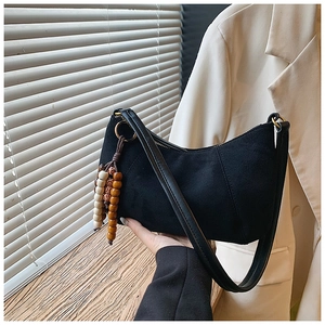 Dettaglio della borsa a mezzaluna in camoscio nero con perline etniche in legno sulla tracolla