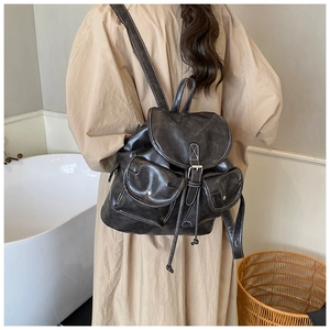Détail d'un sac à dos en cuir marron foncé vintage avec fermeture à cordon et coutures blanches