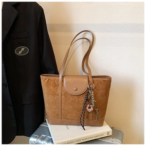 Detail view of brown quilted tote bag with donut charm and leather stitching