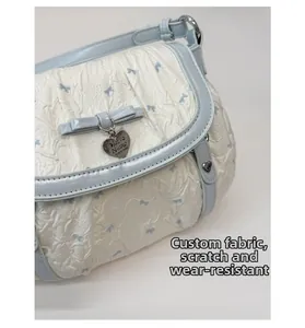 Close-up of bow pattern texture and heart pendant on a blue and white handbag