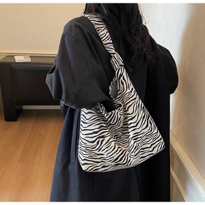 Detail of zebra print canvas tote bag featuring a stylish knotted shoulder strap design