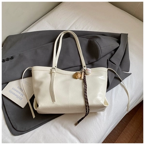 Détail du sac cabas crème avec texture plissée brillante et breloque ours mignon