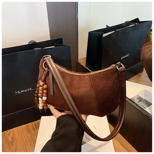 Dettaglio di una borsa hobo in pelle scamosciata marrone scuro con nappe in legno vintage