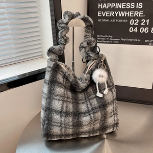 Detailed view of plaid plush tote bag with a soft faux shearling texture and a ball charm
