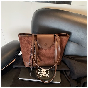 Detail of vintage brown tote bag featuring quilted suede texture and fringe tassel charm