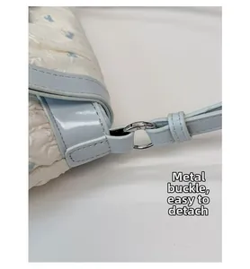 Detail of silver metal buckle on white textured handbag with light blue star pattern