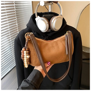 Dettaglio della borsa hobo in pelle scamosciata marrone con pendente di perline