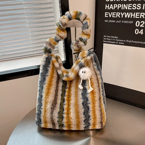 Detail of colorful striped faux fur tote bag with a thick twisted handle and cute plush charm
