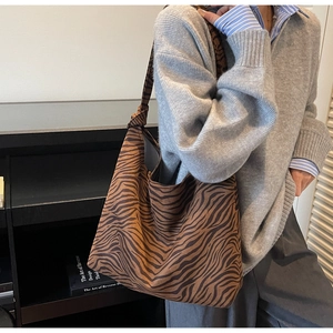 Close-up of zebra print canvas tote bag with knot shoulder strap details on a model