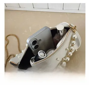 Interior view of white cylindrical pearl handbag showing space for phone and cosmetics