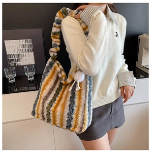 Close-up of colorful striped plush tote bag featuring a white fluffy ball pendant accessory
