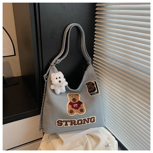 Dettaglio ravvicinato della borsa tote in tela blu con toppe ricamate e ciondolo cane peluche
