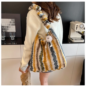 Detail of plush tote bag showing colorful vertical stripes and fuzzy doll pendant