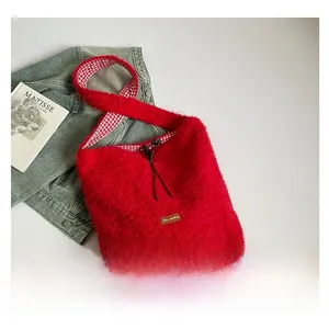 Macro detail of red fuzzy tote bag with plaid lining and leather brand patch