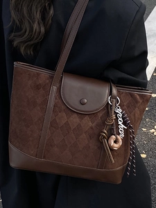 Vintage dark brown quilted tote bag with designer charm shown in an elegant street style look