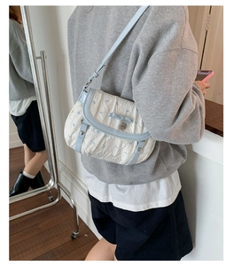 Detail showing white pleated shoulder bag with blue bows and heart charm on a model