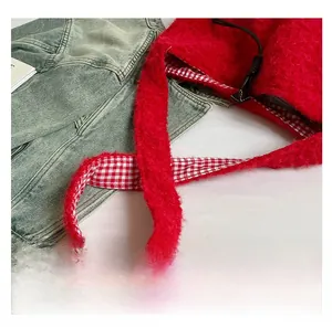 Detail view of red faux fur shoulder bag featuring contrast plaid lining and drawstring closure