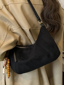 Borsa sottobraccio in pelle scamosciata nera con perline di legno su trench kaki