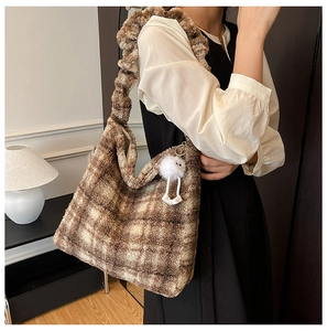 Detail of checkered plush tote bag featuring ruffled strap and white plush pendant