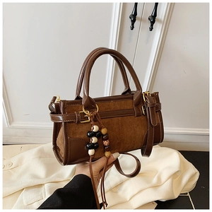 Dettaglio di una borsa baguette marrone scuro con texture miste e ciondolo di perle