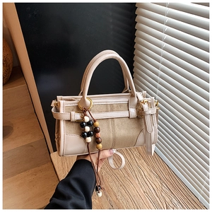 Dettaglio borsa baguette beige con ciondolo in perline di legno e trama in pelle scamosciata