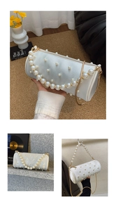 Detail of white barrel bag featuring faux pearl embellishments and golden metal chain