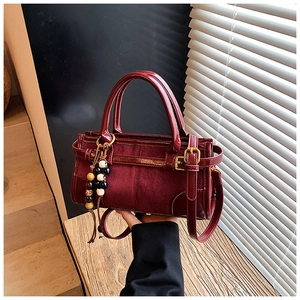 Dettaglio borsa baguette bordeaux con texture in pelle verniciata lucida e pelle scamosciata