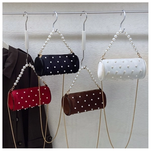 Detail of elegant satin barrel bags with pearl handles and chain straps in four colors