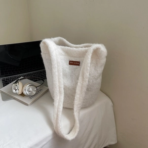 Detail van witte pluche emmertas met bruine lederen patch op een bureau met lifestyle items