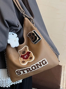 Borsa hobo marrone in ecopelle con toppe vintage e un ciondolo a forma di orsetto