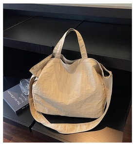 Detail of a large beige commuter tote bag with natural pleated texture on minimalist stand