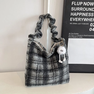 Macro detail of grey plaid faux shearling tote bag with ruffled handle and plush charm