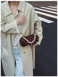 Detail of dark brown leather cylinder bag with pearl embellishments and gold chain strap
