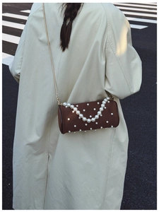 Brown cylinder pearl handbag with gold chain strap shown on beige trench coat model