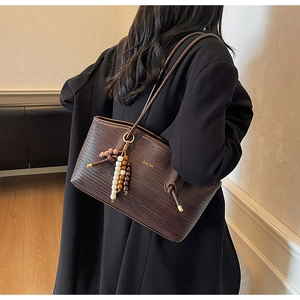 Detail of dark brown woven tote bag with vintage beads and gold logo on leather