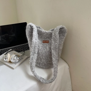 Detailopname van grijze pluche emmertas met lederen label op een witte tafelset